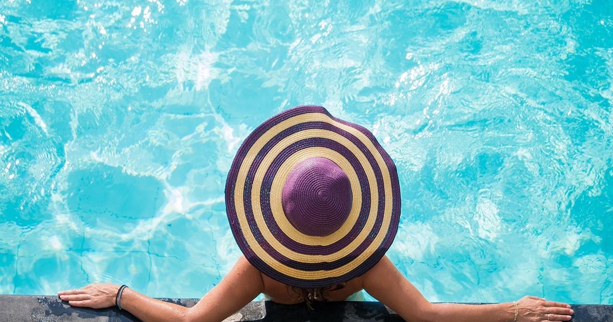 Woman in hat, leaning on pool wall