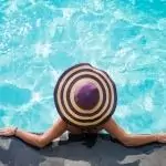Woman in hat, leaning on pool wall