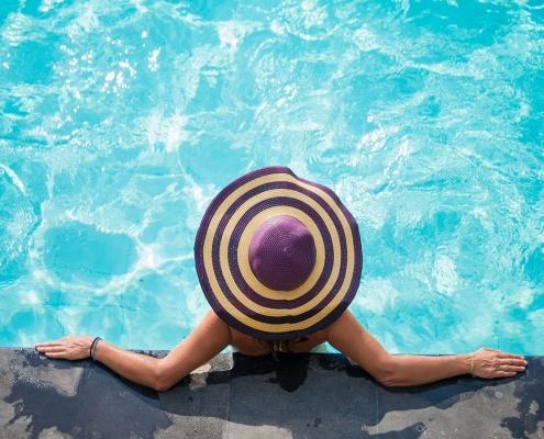 Woman in hat, leaning on pool wall