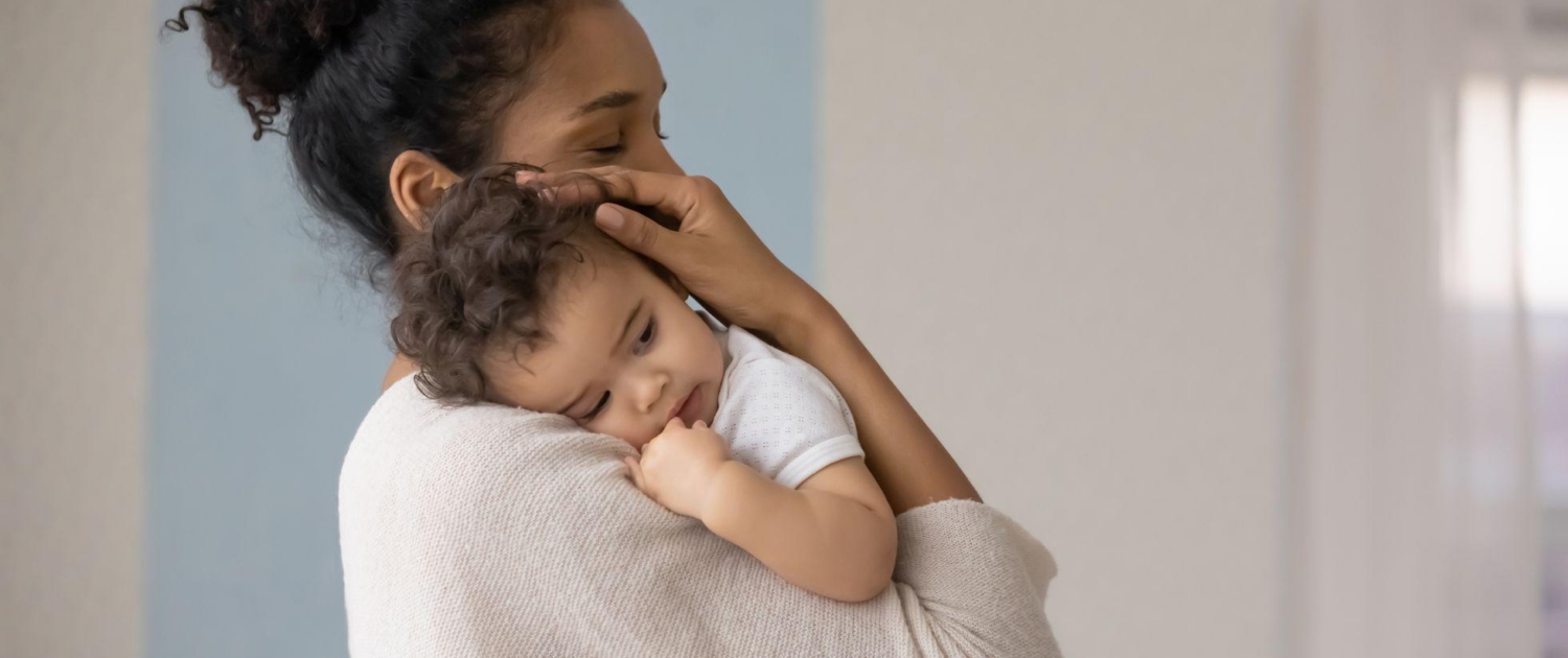 a mother holds her baby and considers how to wean them from breastfeeding.