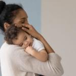 a mother holds her baby and considers how to wean them from breastfeeding.