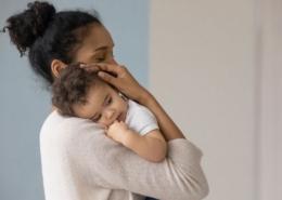 a mother holds her baby and considers how to wean them from breastfeeding.