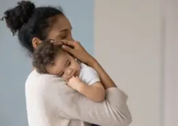 a mother holds her baby and considers how to wean them from breastfeeding.