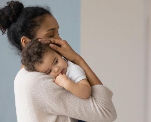 a mother holds her baby and considers how to wean them from breastfeeding.