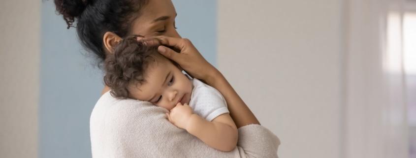 a mother holds her baby and considers how to wean them from breastfeeding.
