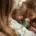 A newborn baby is cuddled by their parent and older sibling.