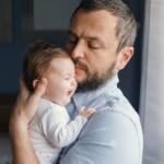 A father tries to soothe his baby as they cry in his arms.