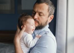 A father tries to soothe his baby as they cry in his arms.
