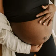 A pregnant person embraces their baby bump