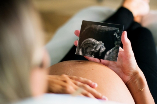 A pregnant person looks at their ultrasound photo while relaxing in their home.