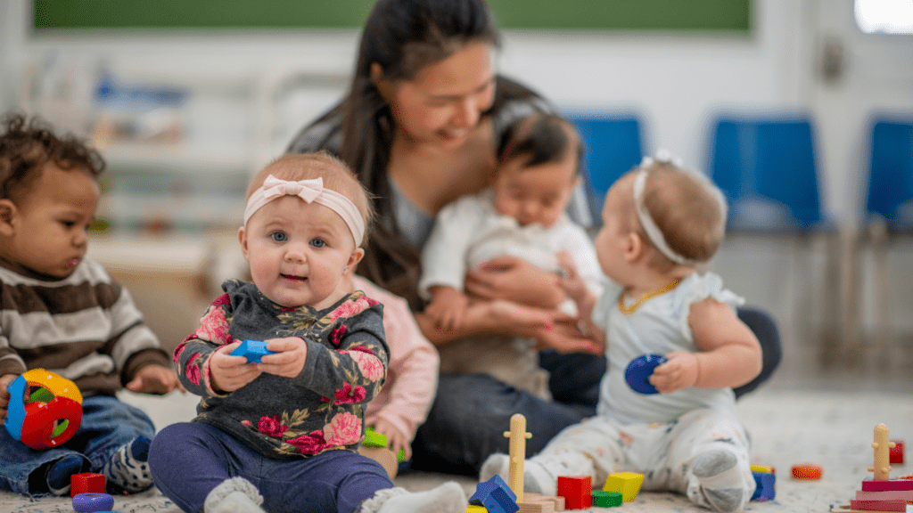 A caregiver sits with babies while their parents return to work.