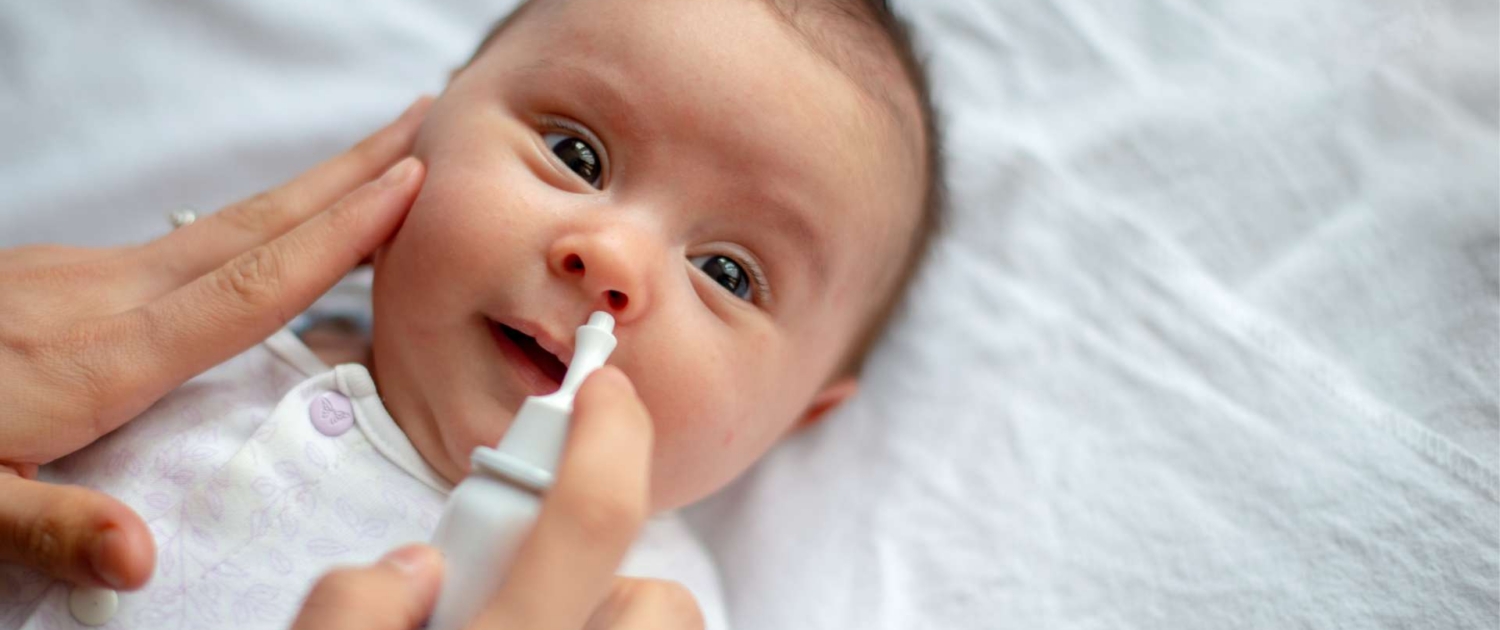Sick baby getting saline nose drops. RSV, flu, covid Baltimore babies and families