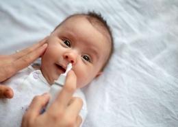 Sick baby getting saline nose drops. RSV, flu, covid Baltimore babies and families