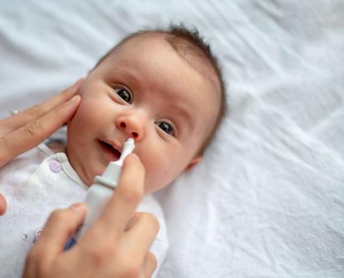 Sick baby getting saline nose drops. RSV, flu, covid Baltimore babies and families