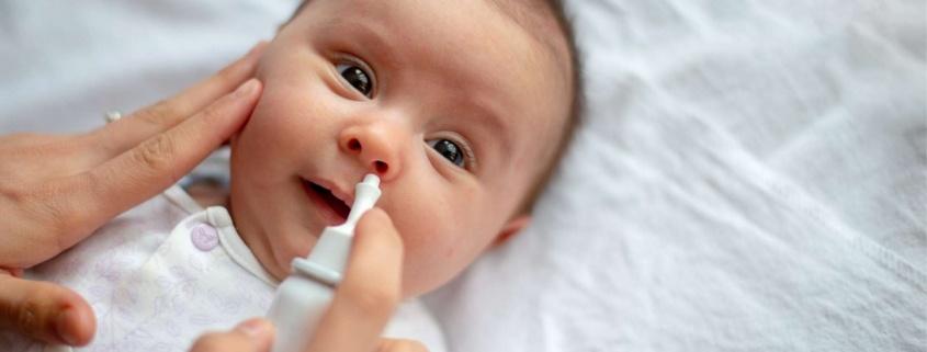 Sick baby getting saline nose drops. RSV, flu, covid Baltimore babies and families