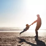 parent and child on a sunny beach, preparing for daylight savings time with baby child