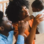 Happy family joyfully looks at their new baby in a nursery.