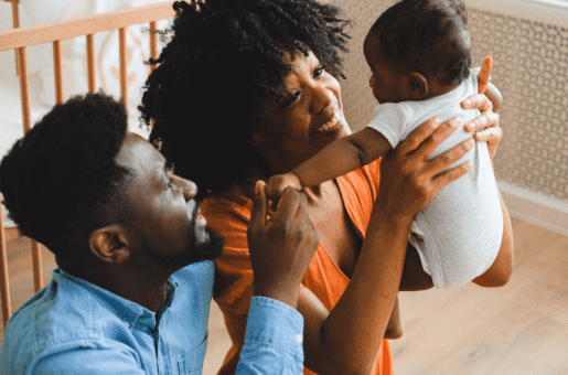 Happy family joyfully looks at their new baby in a nursery.