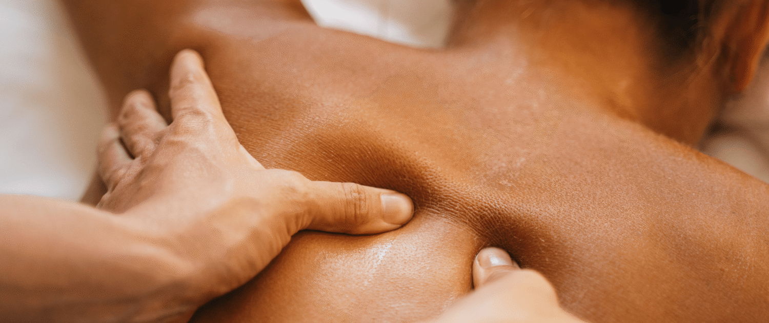 A set of hands massages a client's back who is lying down.