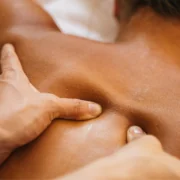 A set of hands massages a client's back who is lying down.