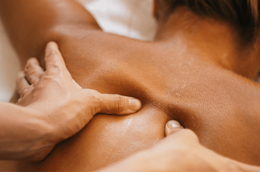 A set of hands massages a client's back who is lying down.