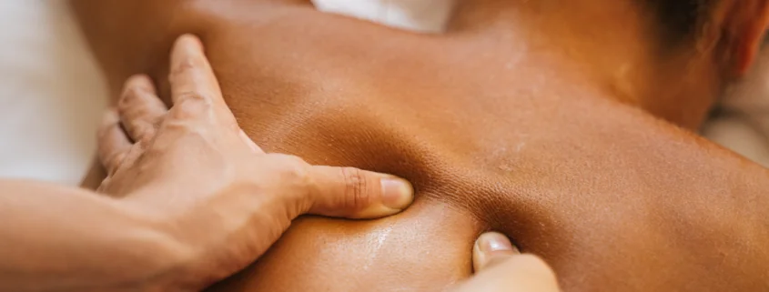 A set of hands massages a client's back who is lying down.
