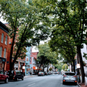 Downtown Frederick, MD street view shows brick buildings and tree-lined street.