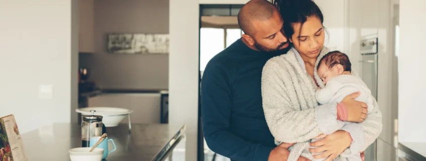 A couple looks at their newborn enjoying the postpartum time together in the kitchen.