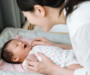 Mother's Day Gift Guide Overnight doula care for a newborn baby who smiles on a mat. Mother's Day Gift Guide