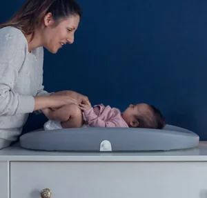 Mother's Day Gift Guide A baby lies on a Hatch changing pad and scale while a caregiver smiles down at them. Mother's Day Gift Guide