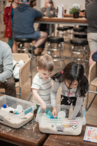 Little ones play with sensory bins alongside their caregivers.