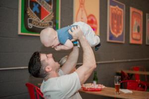 A parent holds their baby above their head playing a game with them.