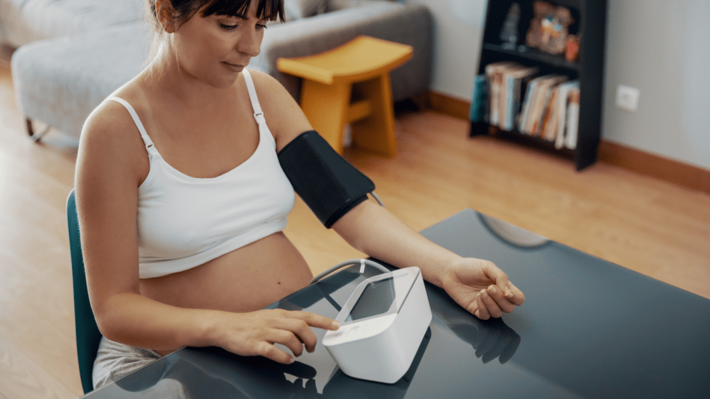 Pregnant individual takes their own blood pressure at home to monitor for hypertension, preeclampsia, and hellp in pregnancy