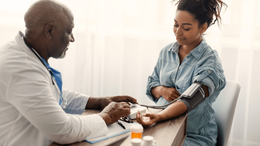 A doctor takes the blood pressure of a pregnant patient in their office.