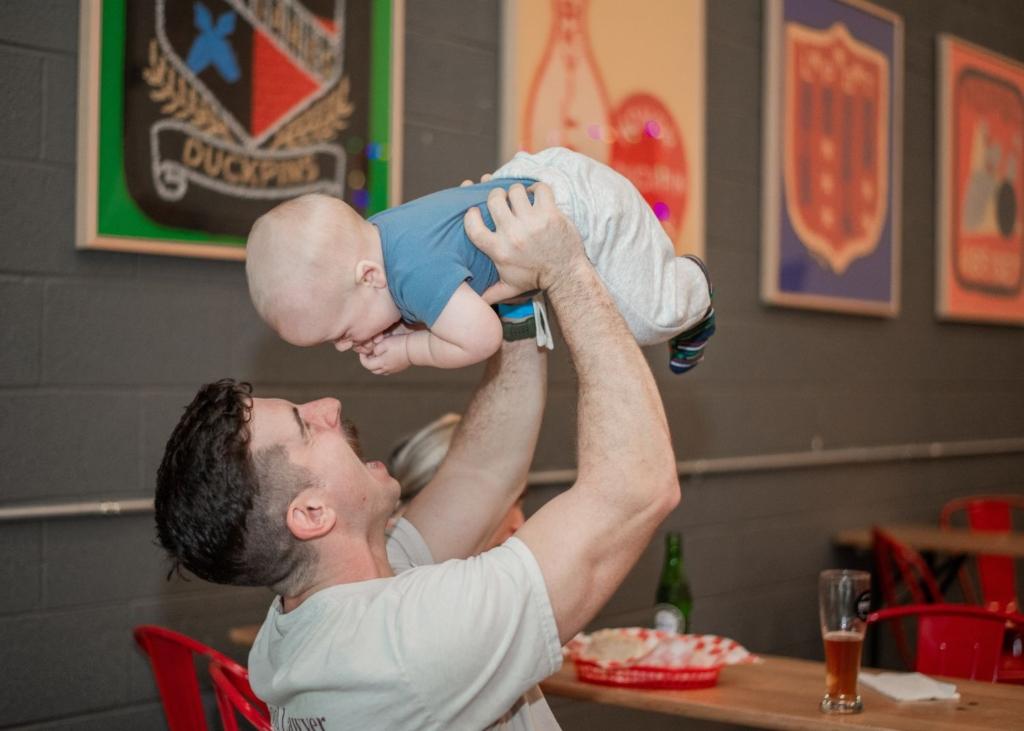 A new parent holds their baby above their head playing a game with them.