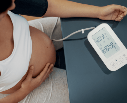 Pregnant individual takes their blood pressure to monitor for hypertension, preeclampsia, or hellp in pregnancy.