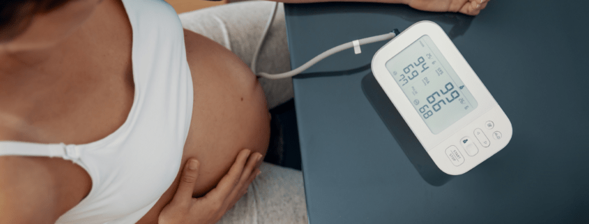 Pregnant individual takes their blood pressure to monitor for hypertension, preeclampsia, or hellp in pregnancy.