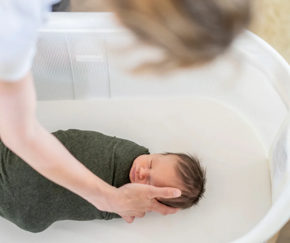 a new parent sets their baby into a bassinet
