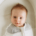 A baby smiles at a camera from a snoo bassinet