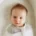 A baby smiles at a camera from a snoo bassinet