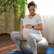 A pregnant person sits on a yoga ball during early labor as a comfort and distraction technique.