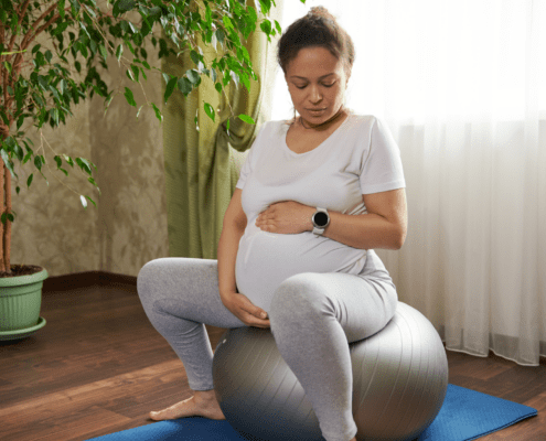 A pregnant person sits on a yoga ball during early labor as a comfort and distraction technique.