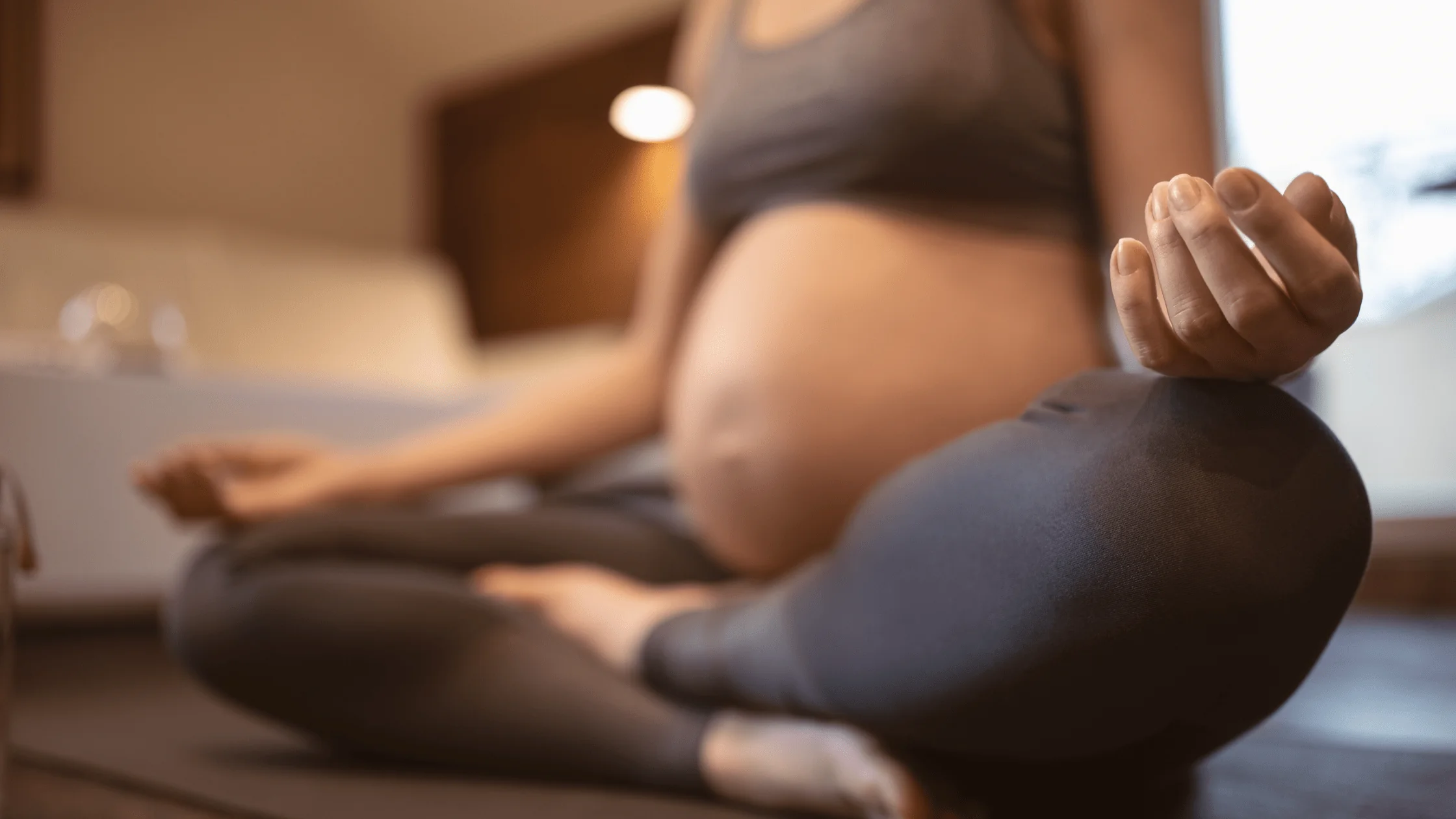 A pregnant individual does a yoga and meditation routine.