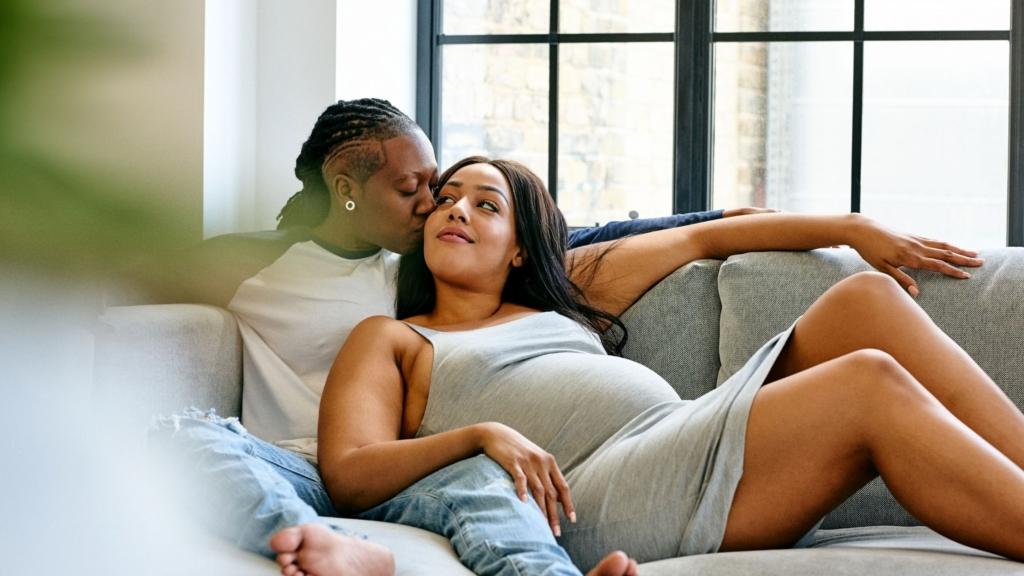 An expectant LGBTQ+ couple lounges together.