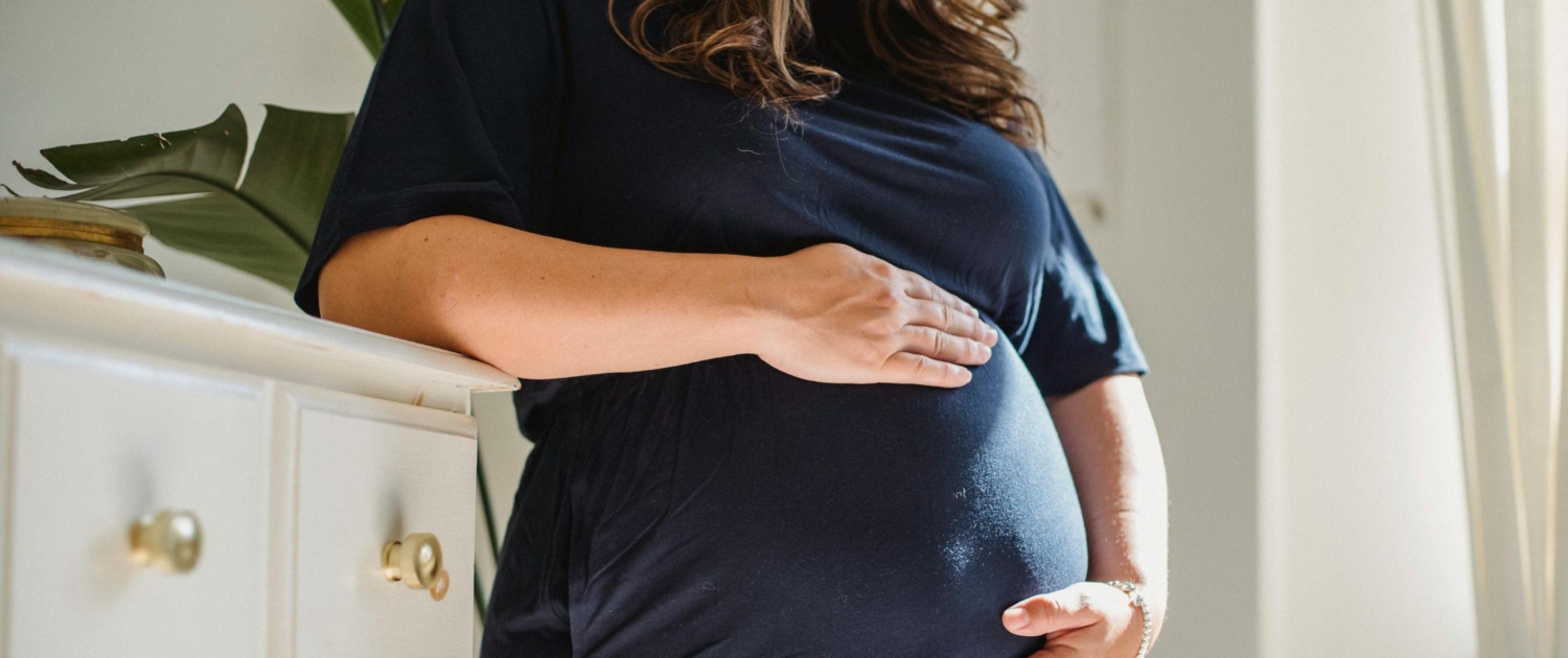 A pregnant person cradles their belly as they contemplate the changes in their body once their baby arrives.