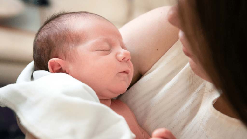 A baby rests peacefully in their mother's arms.