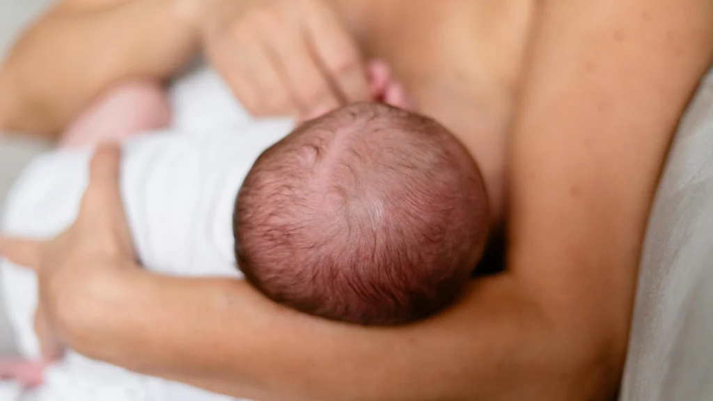 newborn baby's head held by their mother that doesn't feature head molding.