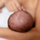 newborn baby's head held by their mother that doesn't feature head molding.