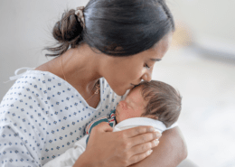 A mother kisses her newborn with moderate head molding.