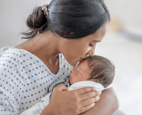 A mother kisses her newborn with moderate head molding.